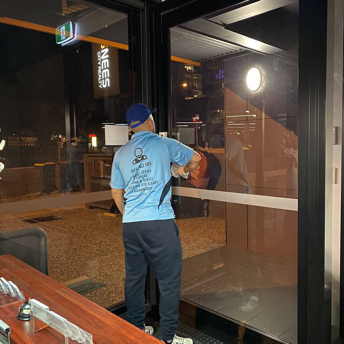 Polishing shopfront glass at night
